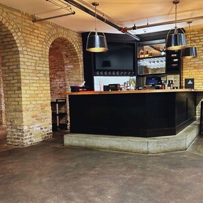 A bar area with a brick wall, a black counter, and hanging lights.
