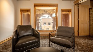 A room with two leather chairs, a small table, and a large window with a view of a brick building. - Hotel Donaldson (Fargo)