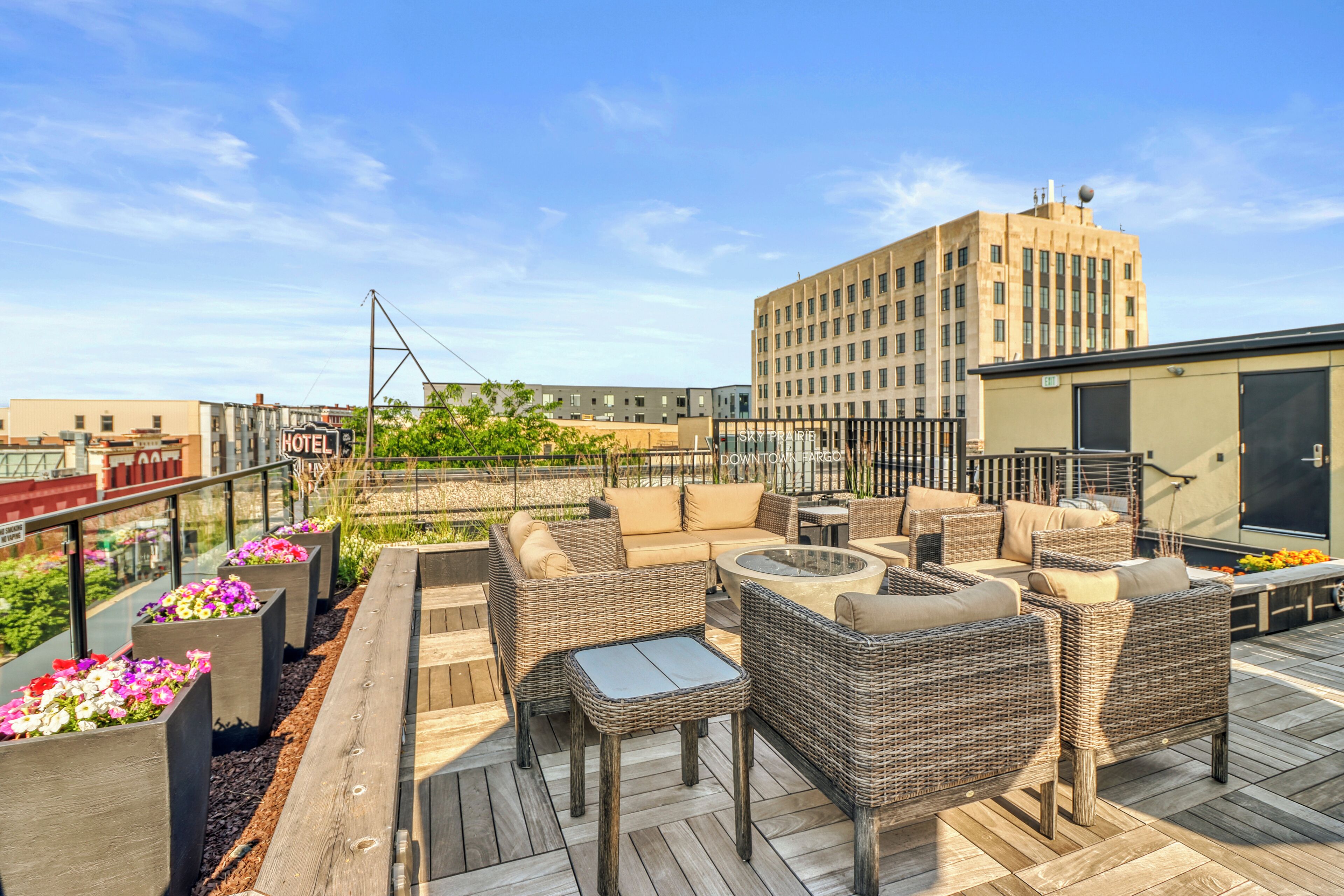 A rooftop patio with wicker furniture and flower planters.