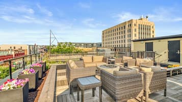 A rooftop patio with wicker furniture and flower planters.