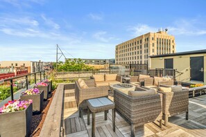 A rooftop patio with wicker furniture and flower planters.