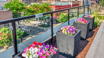 Terrassa al terrat amb planters florals i barana de vidre amb vista a un paisatge urbà.