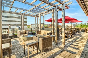 An outdoor patio with wooden flooring, wicker furniture, and red umbrellas. - Hotel Donaldson (Fargo)