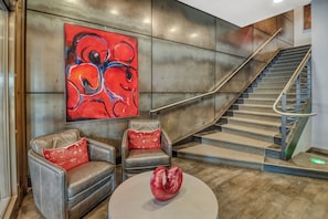 A modern lobby with a staircase, leather armchairs, a red abstract painting, and a unique red sculpture. - Hotel Donaldson (Fargo)