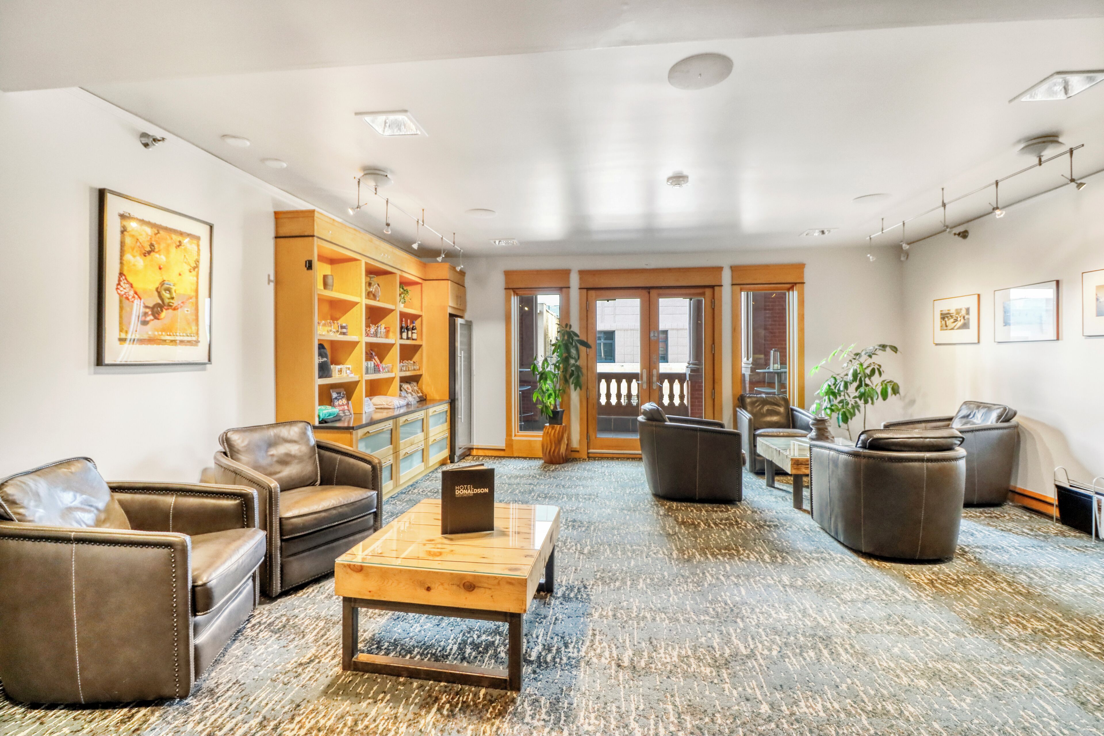 A spacious lobby with leather sofas, a wooden coffee table, and a bookshelf.