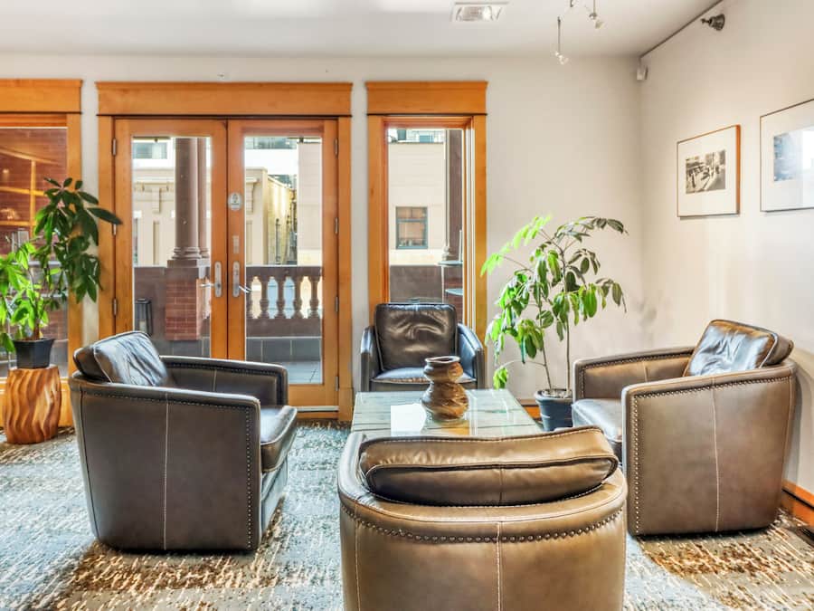 Una habitación con sofás de cuero, una mesa de centro de vidrio y plantas en macetas.