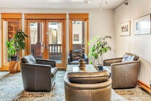 A room with leather sofas, a glass coffee table, and potted plants.