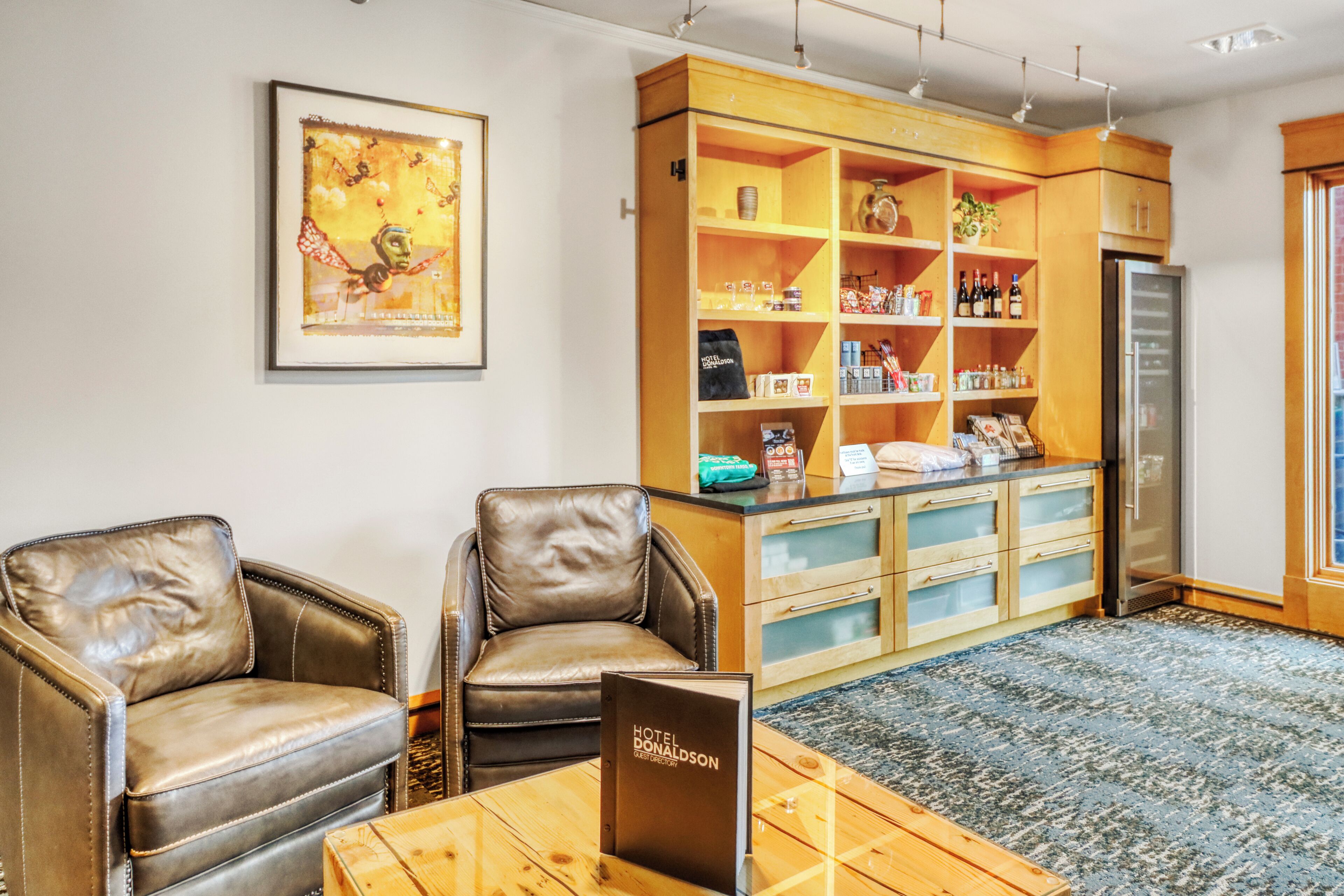 Um saguão de hotel com poltronas de couro, um balcão de recepção de madeira e um quadro emoldurado na parede.