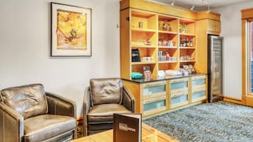 Um saguão de hotel com poltronas de couro, um balcão de recepção de madeira e um quadro emoldurado na parede.