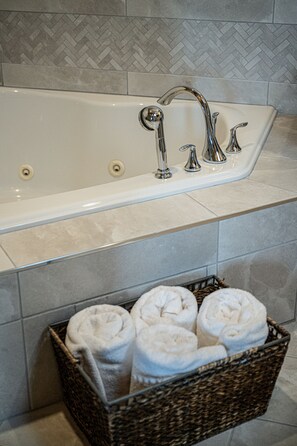 A bathroom with a bathtub, two faucets, and a wicker basket with towels. - Hotel Donaldson (Fargo)