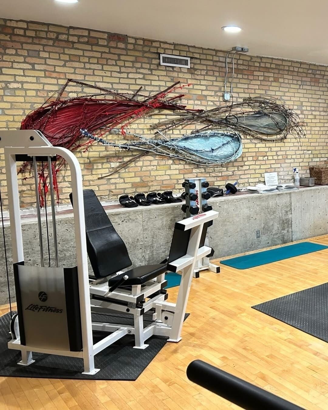 Et fitnessrum med træningsudstyr, en murstensvæg og et trægulv.