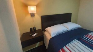 A hotel room with a bed, a nightstand, a lamp, and an air conditioning unit. - Refugio Acolchado: Habitaciones Dobles para Humanos y Peludos Compañeros (Ciudad Madero)