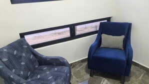 A room with a patterned armchair and a blue armchair with a patterned pillow. - Refugio Acolchado: Habitaciones Dobles para Humanos y Peludos Compañeros (Ciudad Madero)