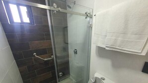 A modern bathroom with a glass shower enclosure, a toilet, and a towel rack. - Refugio Acolchado: Habitaciones Dobles para Humanos y Peludos Compañeros (Ciudad Madero)