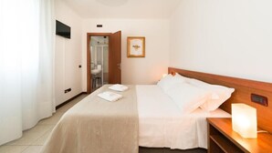 A hotel room with a bed, a nightstand, a bedside lamp, a framed picture on the wall, and a bathroom visible through an open door. - La Lista Rooms Venice CO Doge Veneziano (Mestre)