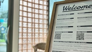 A framed welcome sign with room information, a view of a window with a grid pattern, and a small bell on a table. - La Lista Rooms Venice CO Doge Veneziano (Mestre)