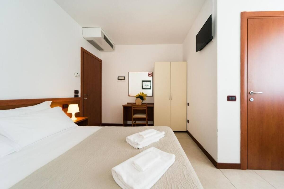 Une chambre d’hôtel avec un lit, un bureau, une chaise, une armoire et une porte.