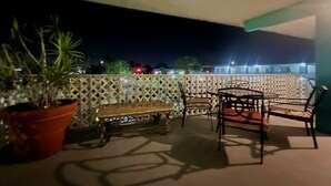 A balcony with a table and chairs, a potted plant, and a wooden bench. - Bposhtels Clearwater Tampa (Clearwater)