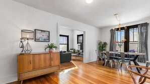 A spacious living area with a wooden floor, a dining table with chairs, a sofa, a cabinet, and a chandelier. - Restored farmhouse in Old Town Loveland

 (Loveland)