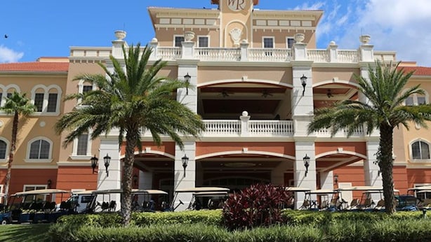 Un hôtel doté d’une entrée imposante, de nombreux balcons et de palmiers.