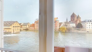 A view of a river with buildings and a tower across it. - Bail Mobilité - Finkwiller (Strasbourg)