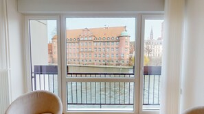 A room with a large window overlooking a river and a historic building. - Bail Mobilité - Finkwiller (Strasbourg)
