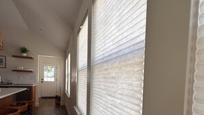 A kitchen with a long counter, wooden stools, and a window with blinds. - Quick walk to private beach from this brand new 3-bedroom cottage (Wareham)
