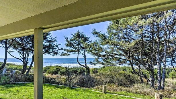 Ein überdachter Außenbereich mit Blick auf das Meer und Bäume.