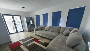 Ein modernes Wohnzimmer mit einem Ecksofa, einem gemusterten Teppich und einem Fernseher.