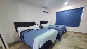 Ein Hotelzimmer mit zwei Betten, einem großen Fenster mit Jalousien und einem Fliesenboden.