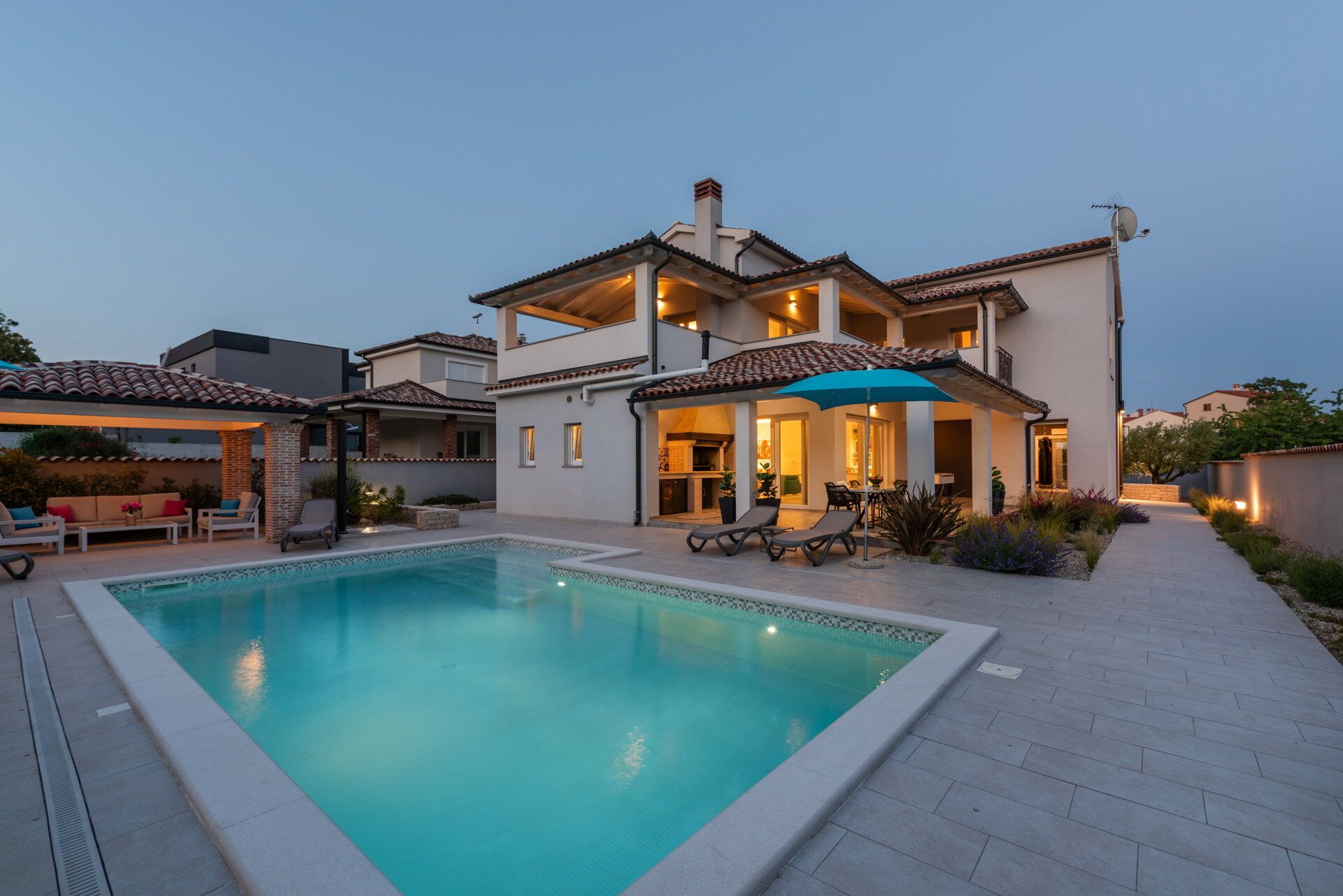 Une maison à deux étages dotée d’une piscine, d’un espace salon extérieur et d’un patio couvert.