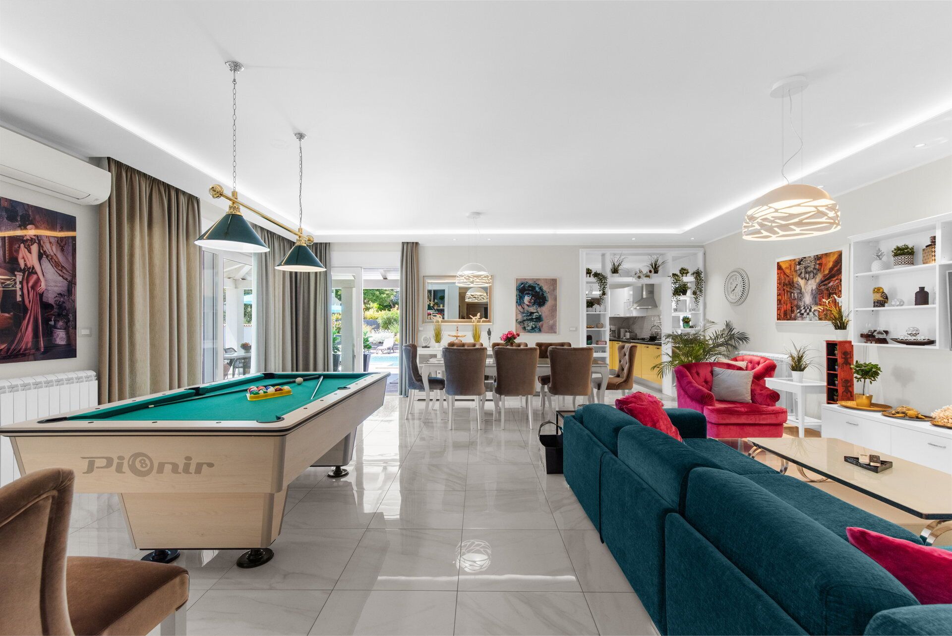 A modern living room with a pool table, a sofa, and a dining area.