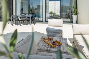 Ein moderner Außenbereich mit Korbmöbeln, einem Tablett für Kaffee und Blick auf Pool und Garten.