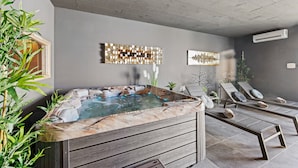A modern spa area with a hot tub, lounge chairs, and decorative wall art. - Luxury Villa Maroon with Pool (Medulin)