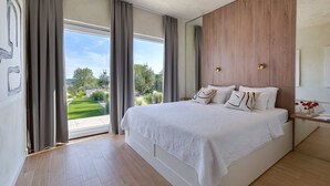 A modern bedroom with a large bed, wooden panel wall, and a view of a green landscape. - Villa Atticora with Pool (Radašinovci)