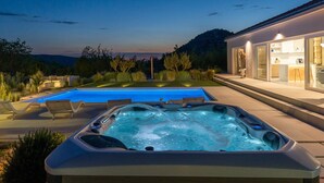 A modern outdoor pool area with a hot tub and a well-lit patio adjacent to a house. - Villa Atticora with Pool (Radašinovci)