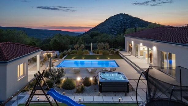 A modern outdoor pool area with a hot tub, a slide, and a patio with seating. - Villa Atticora with Pool (Radašinovci)