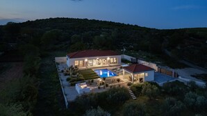A modern house with a swimming pool, a covered patio, and a view of a hilly landscape. - Villa Atticora with Pool (Radašinovci)