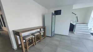 Eine moderne Küche mit einer Holbank und Hockern, einem Kühlschrank und einer Treppe, die in einen oberen Bereich führt.