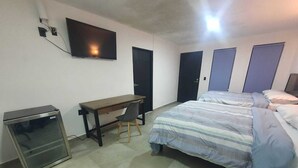 Ein Schlafzimmer mit Bett, Schreibtisch, Stuhl, Fernseher und Kleiderschrank.