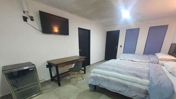 A bedroom with a bed, a desk, a chair, a TV, and a wardrobe.