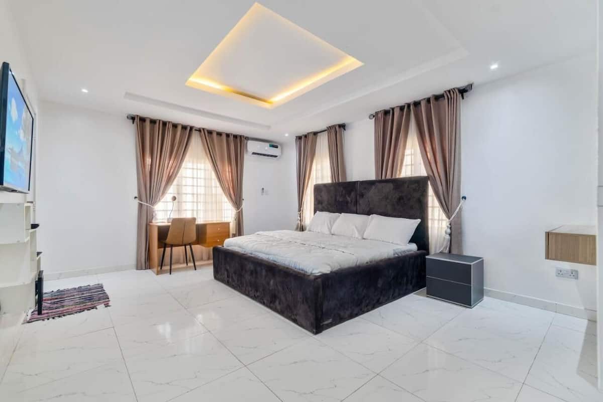 A modern bedroom with a large bed, a desk, and a chair.