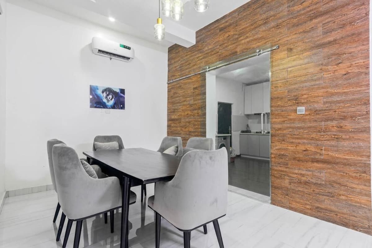 A modern dining area with a wooden accent wall, a glass partition, and a mounted air conditioner.