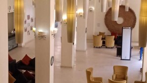 Eine Hotelhalle mit Empfangstresen, einer Sitzecke und einer großen Wanddekoration.