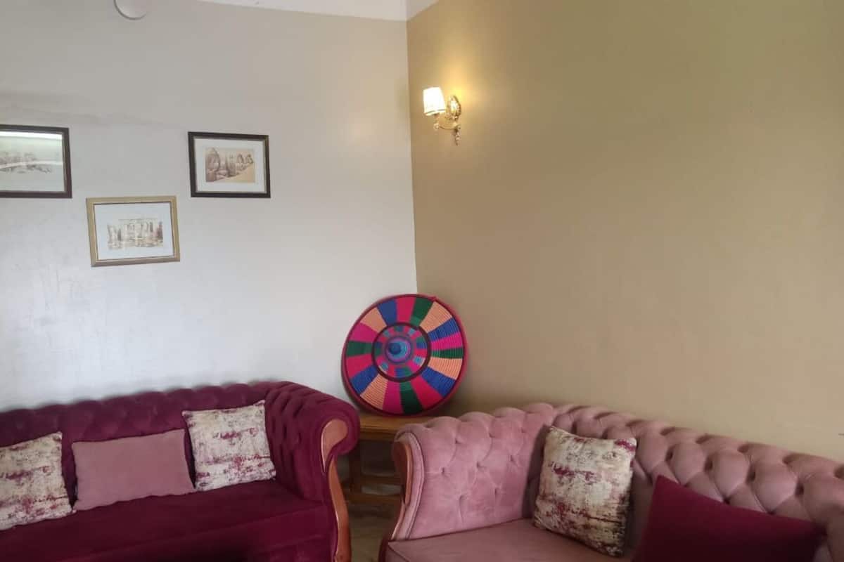 Ein Wohnzimmer mit zwei bequemen Sofas, einer farbenfrohen Wanddekoration und gerahmten Bildern an der Wand.