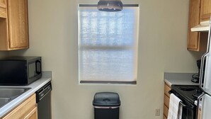 A kitchen with wooden cabinets, a microwave, a dishwasher, a stove, and a trash can. - 2 Bdr 1 Bath Mountain View House (Tucson)