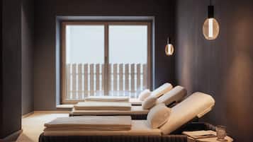 Relax in a serene space with a massage table and chair, overlooking a tranquil outdoor area through a large window.