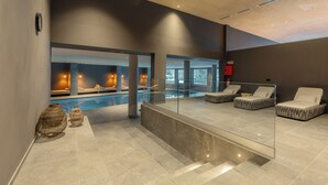 A modern spa area with a pool, lounge chairs, and a glass barrier.