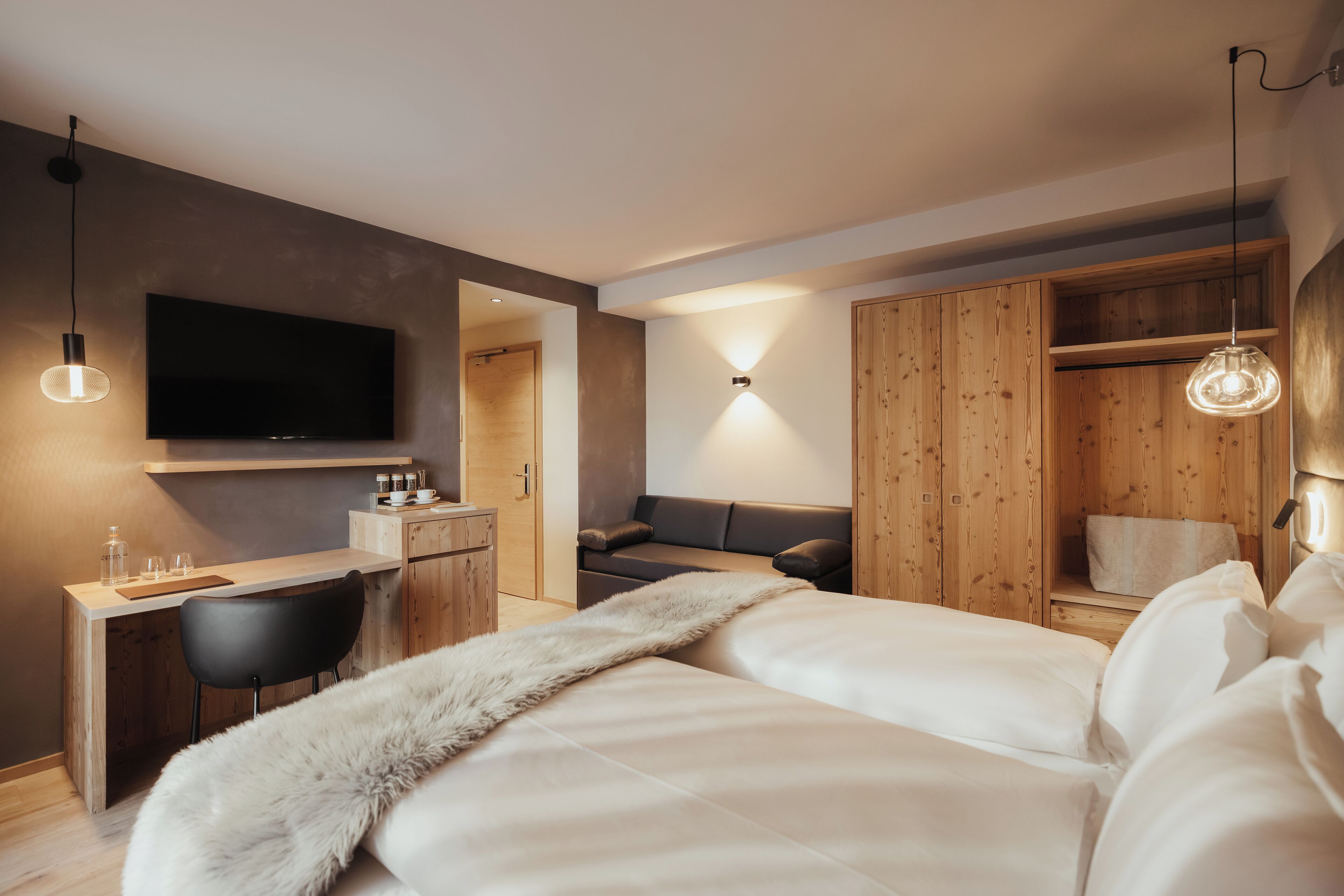 Un dormitorio moderno con cama, escritorio, silla, televisor y armarios de madera.