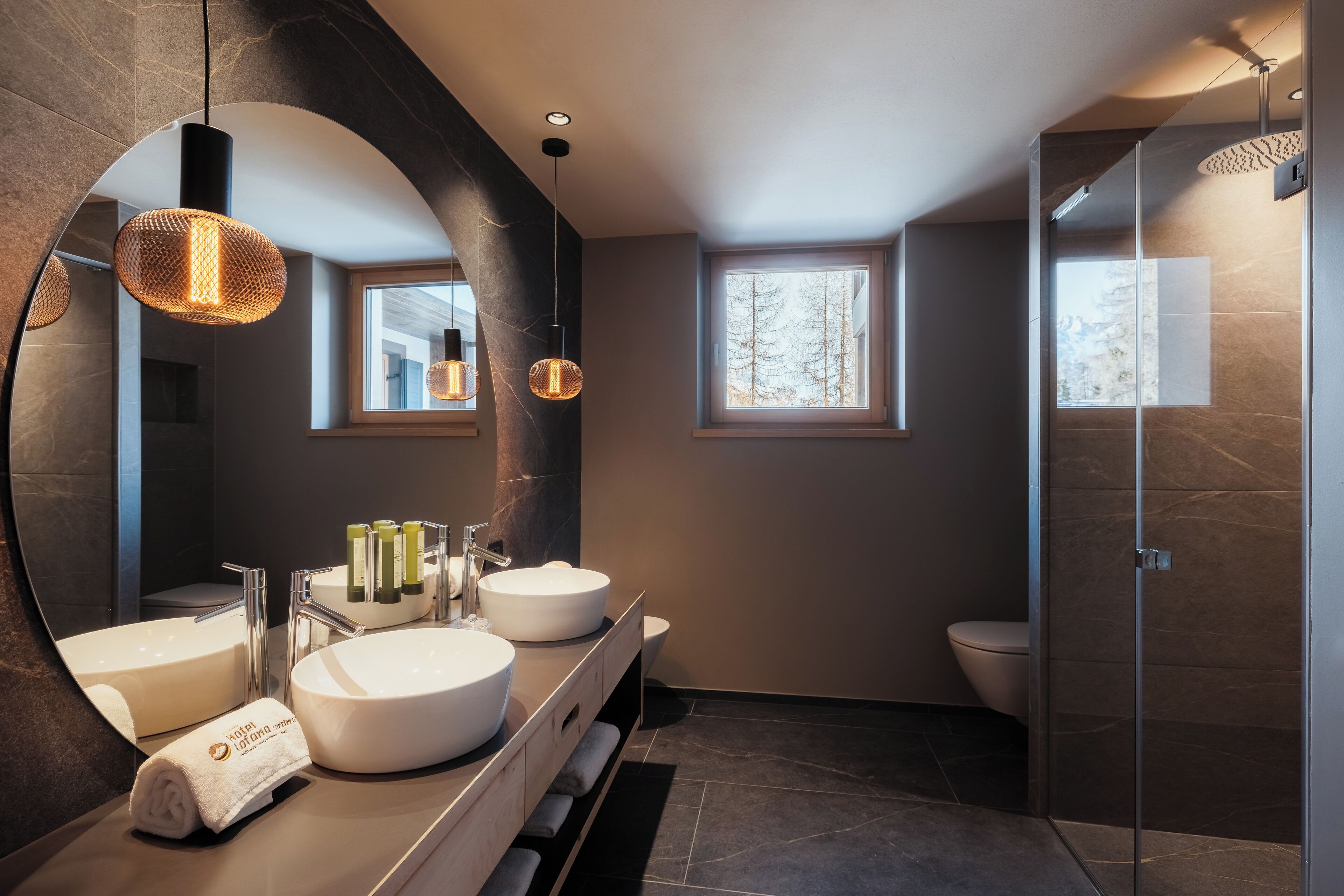 Ein modernes Badezimmer mit zwei runden Waschbecken, einem großen Spiegel und einer Duschkabine.